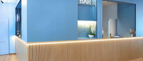 A reception desk with a 'BAR' sign, a potted plant, and a laptop on the counter.