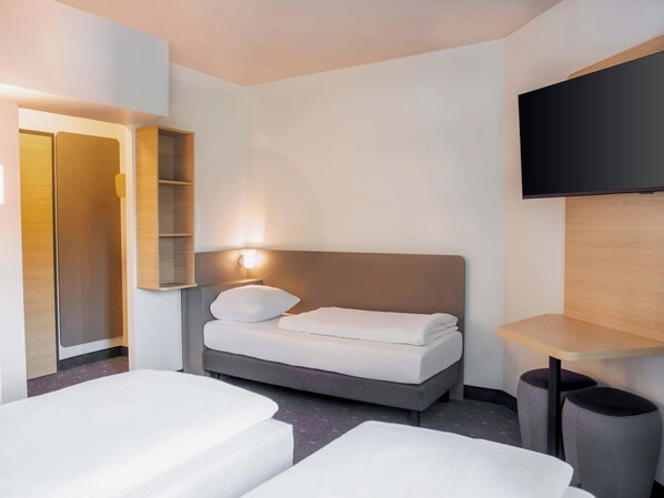 Habitación de hotel con cama, televisor montado en la pared y armario con espejo.