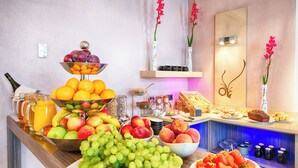 Un buffet proposant une variété de fruits, une bouteille de vin et un coin café.