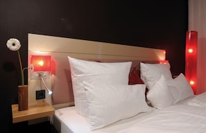 Experience a serene retreat with a neatly made bed, bedside table, and wall-mounted nightstand.
