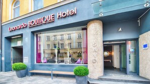 L’extérieur du Leonardo Boutique Hotel se caractérise par de grandes fenêtres, un banc placé à l’extérieur et deux plantes en pot.