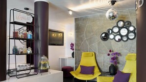 Un espace d’accueil avec un panneau indiquant un bar à bonbons, un téléviseur et un mur orné de miroirs ronds.
