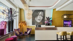 Un espace bar moderne comprenant un comptoir, deux chaises violettes et une grande œuvre d’art murale.