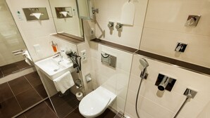 A modern bathroom with a glass-enclosed shower, a white sink, and a toilet. - Hotel Antares (Munich)