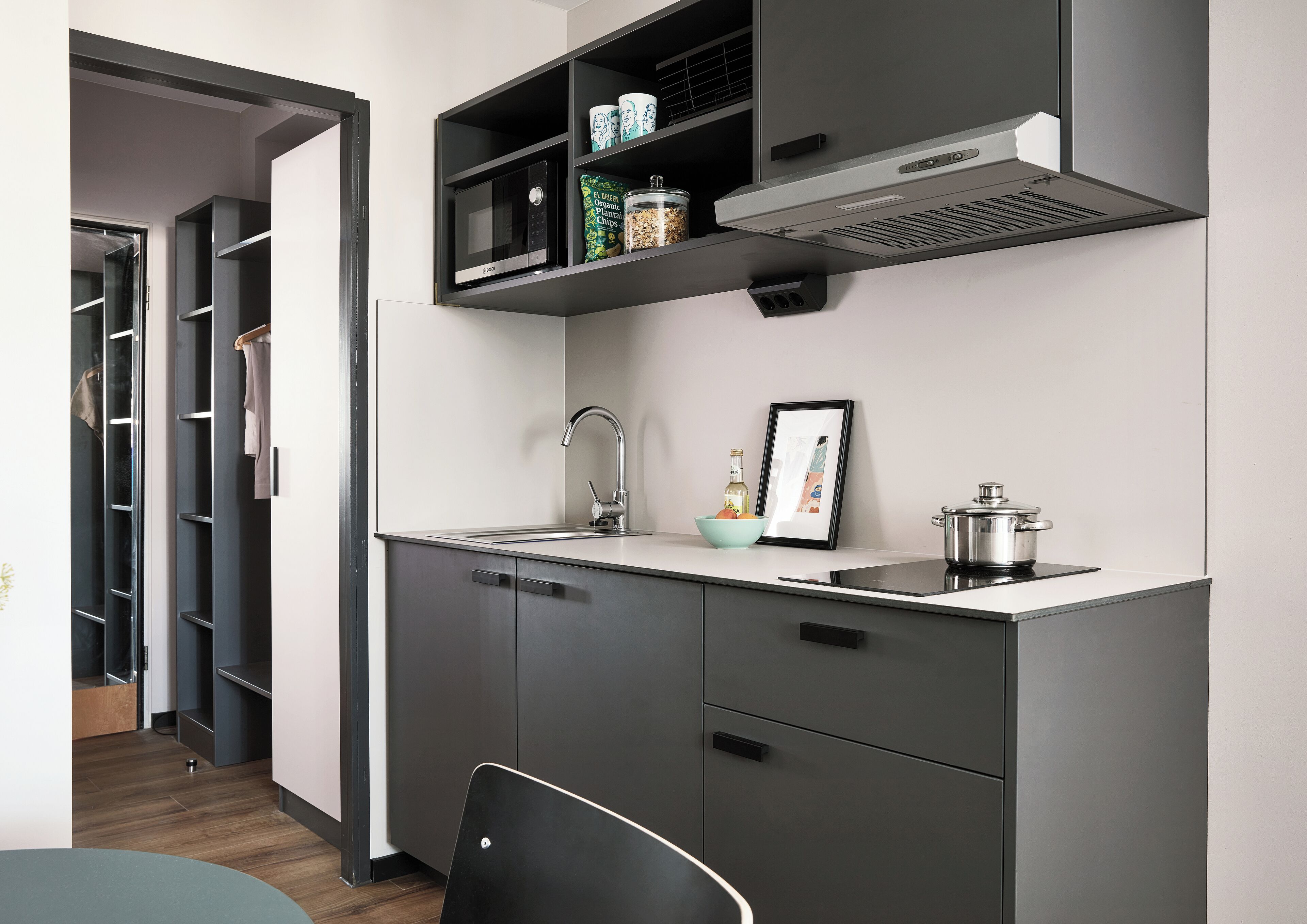 A modern kitchen with a built-in microwave, a stainless steel sink, and a pot on the stove.