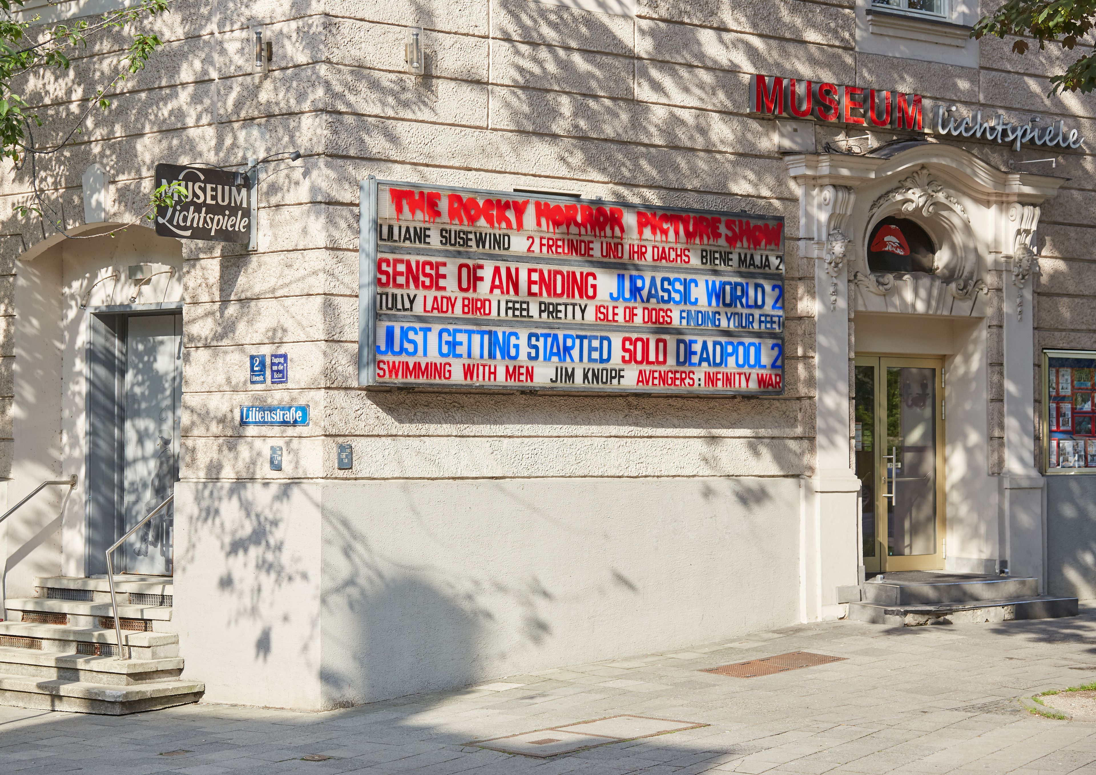 A museum entrance with a sign listing movie showings.