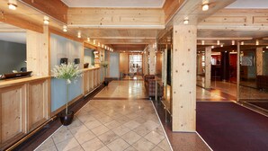 Un vestíbulo de hotel con paneles de madera, una recepción, un área de descanso y un bar.
