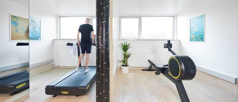 A gym with a treadmill, a stationary bike, and a large mirror.