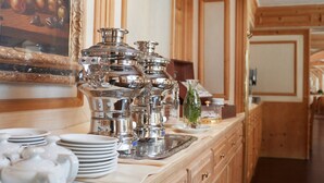 Una cocina con armarios de madera, un cuadro grande de frutas y cubiertos y vajilla sobre la encimera.