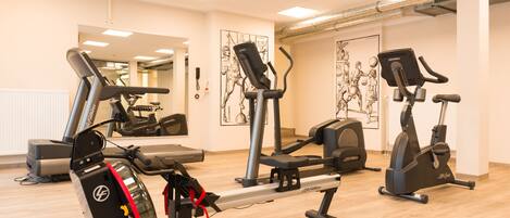 Un gimnasio con máquinas de cardio, espejos y obras de arte en las paredes.