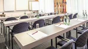 A conference room with long tables, chairs, and a whiteboard.