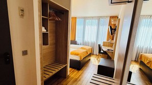A hotel room with a wooden wardrobe, a bed, a desk, and a chair.
