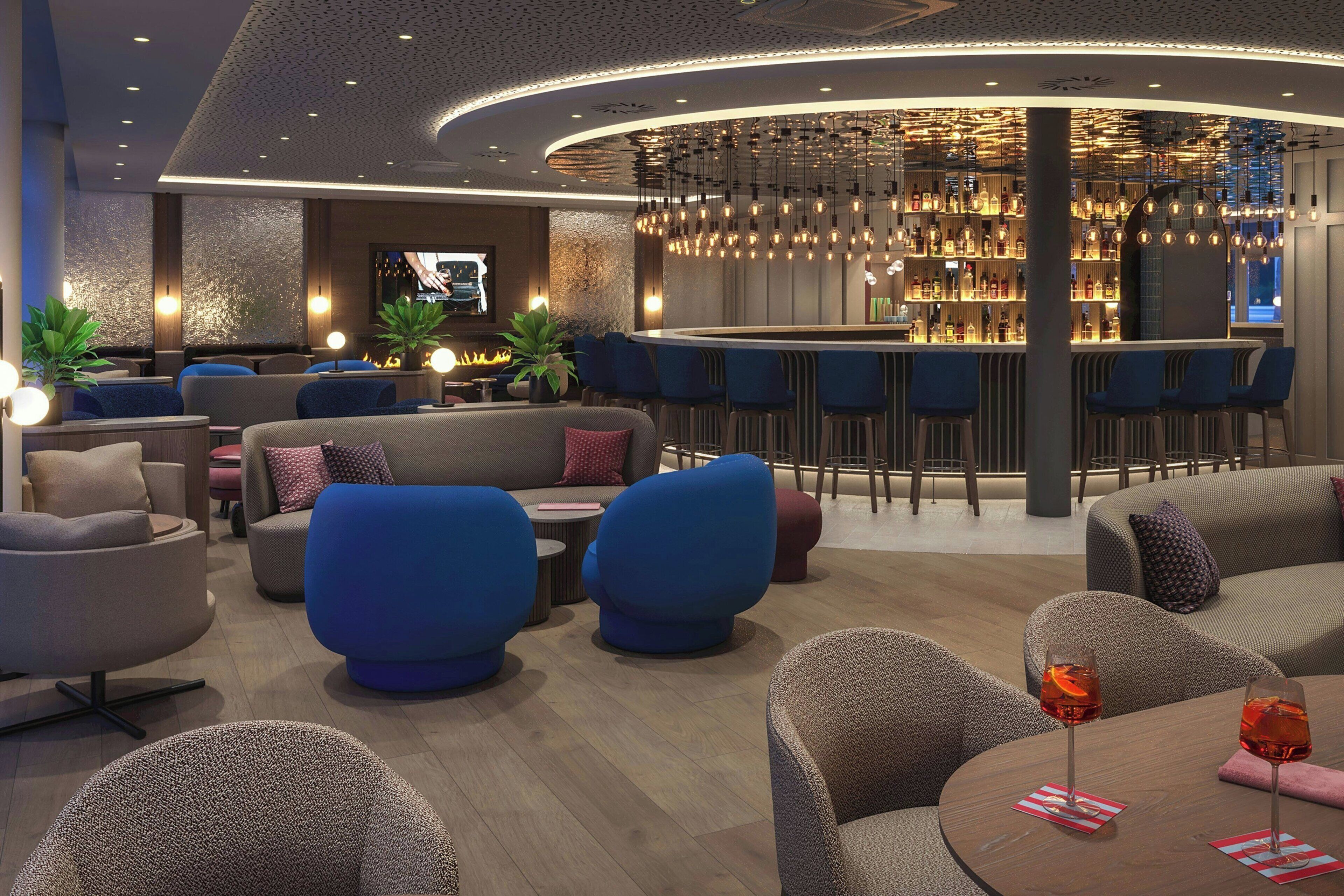 A modern lounge area with sofas, a bar, and a television screen.