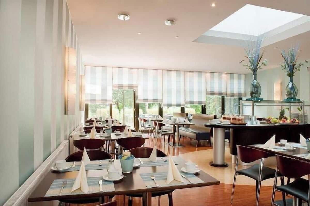 A spacious dining area with multiple tables and chairs, large windows, and a central bar area.