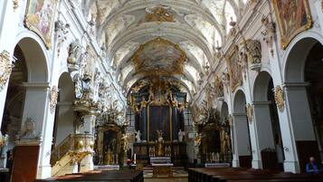 An ornate church interior with high ceilings, detailed frescoes, and a central altar.