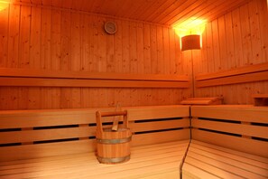 A wooden sauna with benches and a wooden bucket. - Atrium im Park Hotel Regensburg (Regensburg)