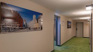 Ein Flur mit grünem Teppich, einem großen Wandbild und einer Tür.