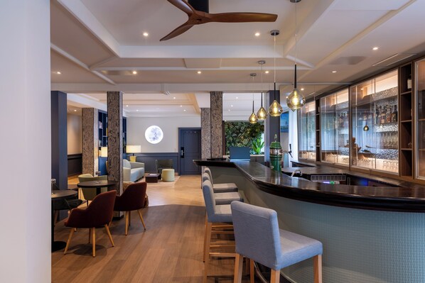 A modern bar area with a curved counter, bar stools, and pendant lighting.