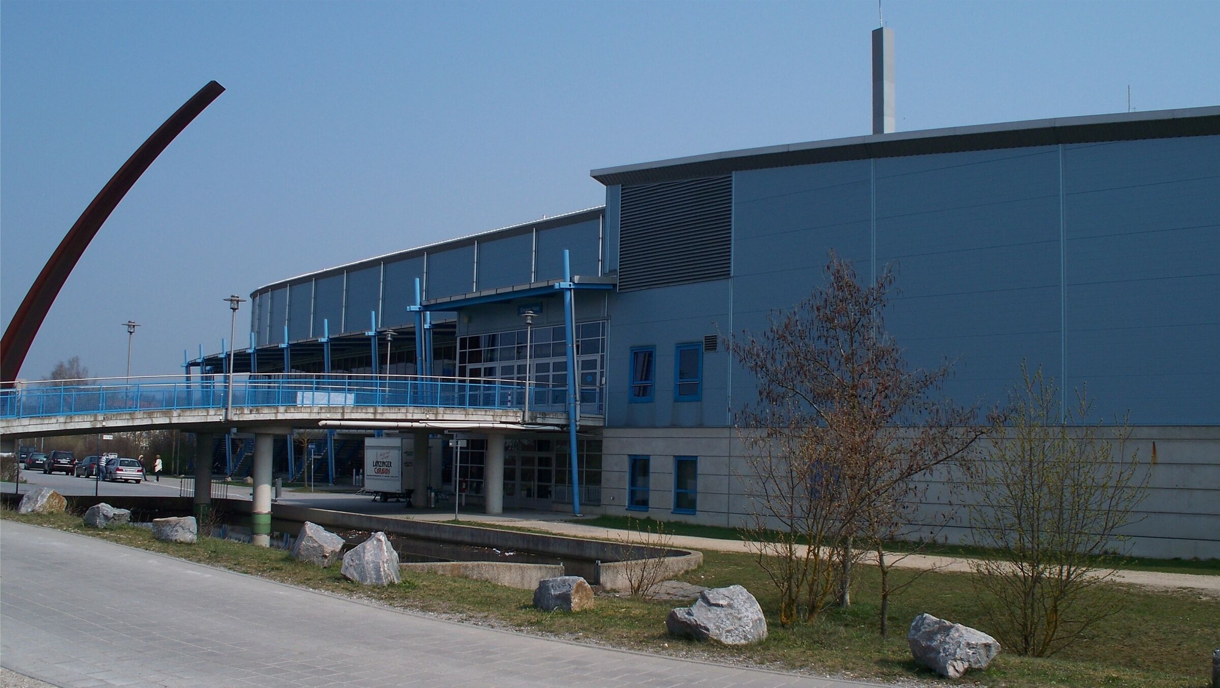 A modern building with a covered walkway, large windows, and a blue exterior.