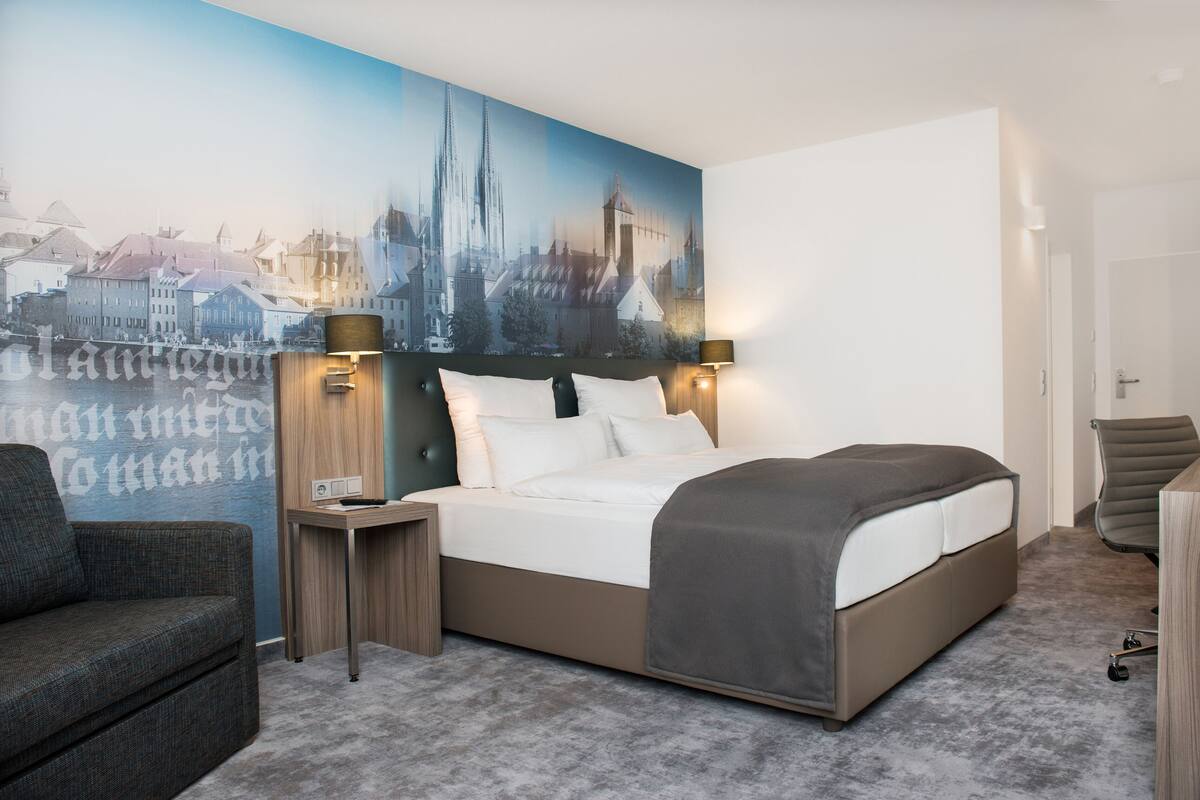Une chambre d’hôtel avec un grand lit, une table de chevet, une chaise et un bureau.