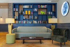 A living room with a sofa, a coffee table, two lamps, a bookshelf, and a wall-mounted circular artwork. - Likestay Regensburg (Regensburg)