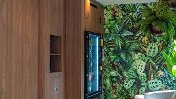 Ein modernes Wohnzimmer mit einer Wand in Holzoptik, einem Flachbildfernseher, einer Couch und einem grünen Kunstgrase-Boden.
