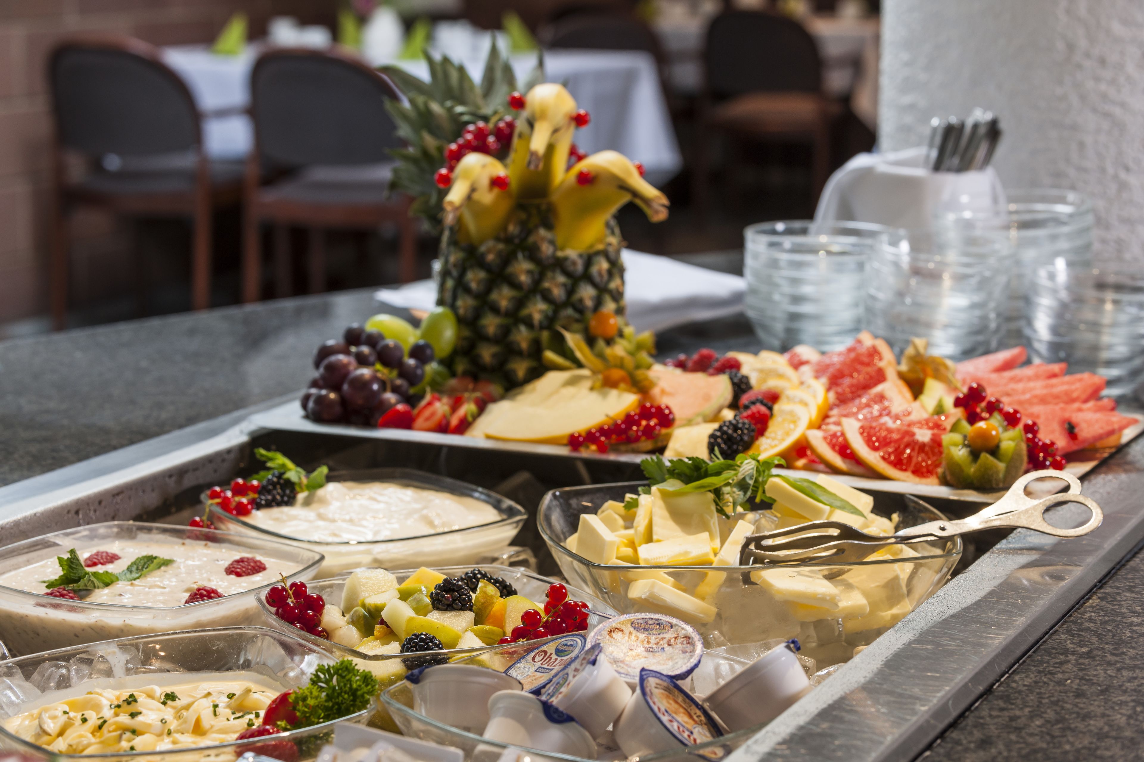 A buffet with various fruits, cheeses, and desserts.