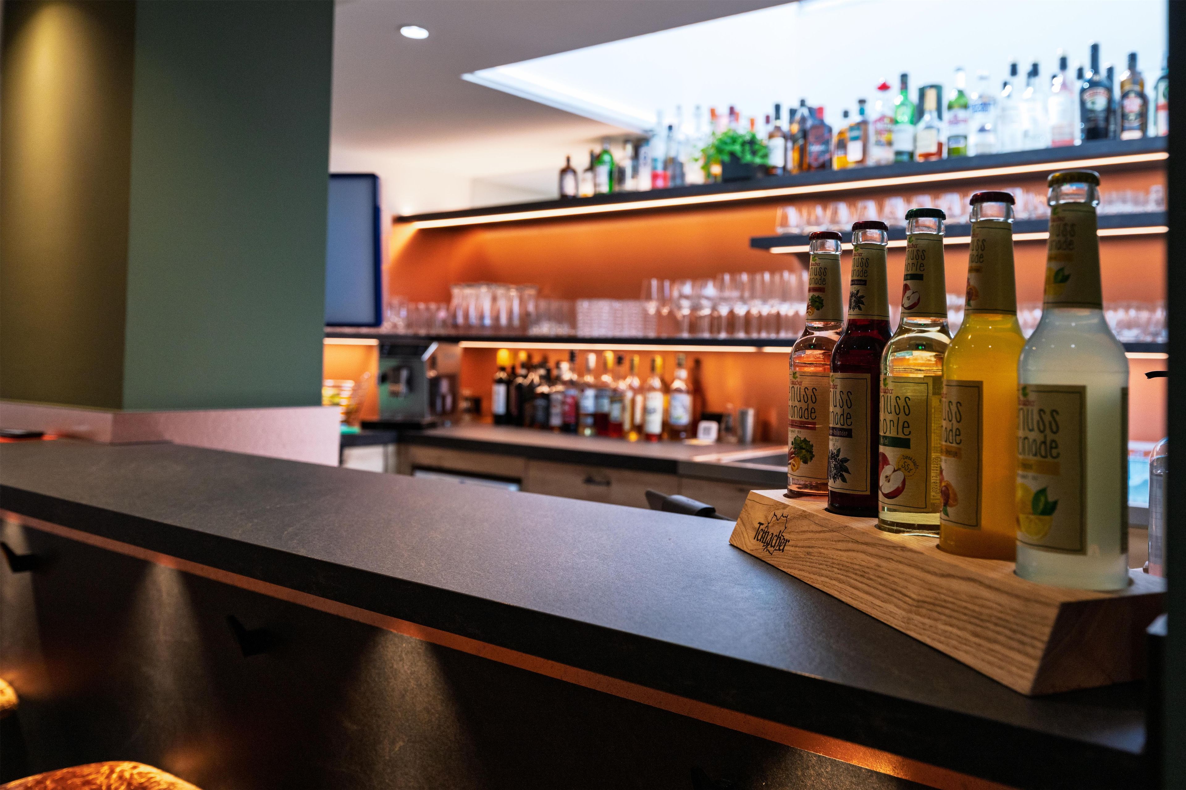 Una zona de bar con botellas de alcohol en estanterías y un expositor de madera.