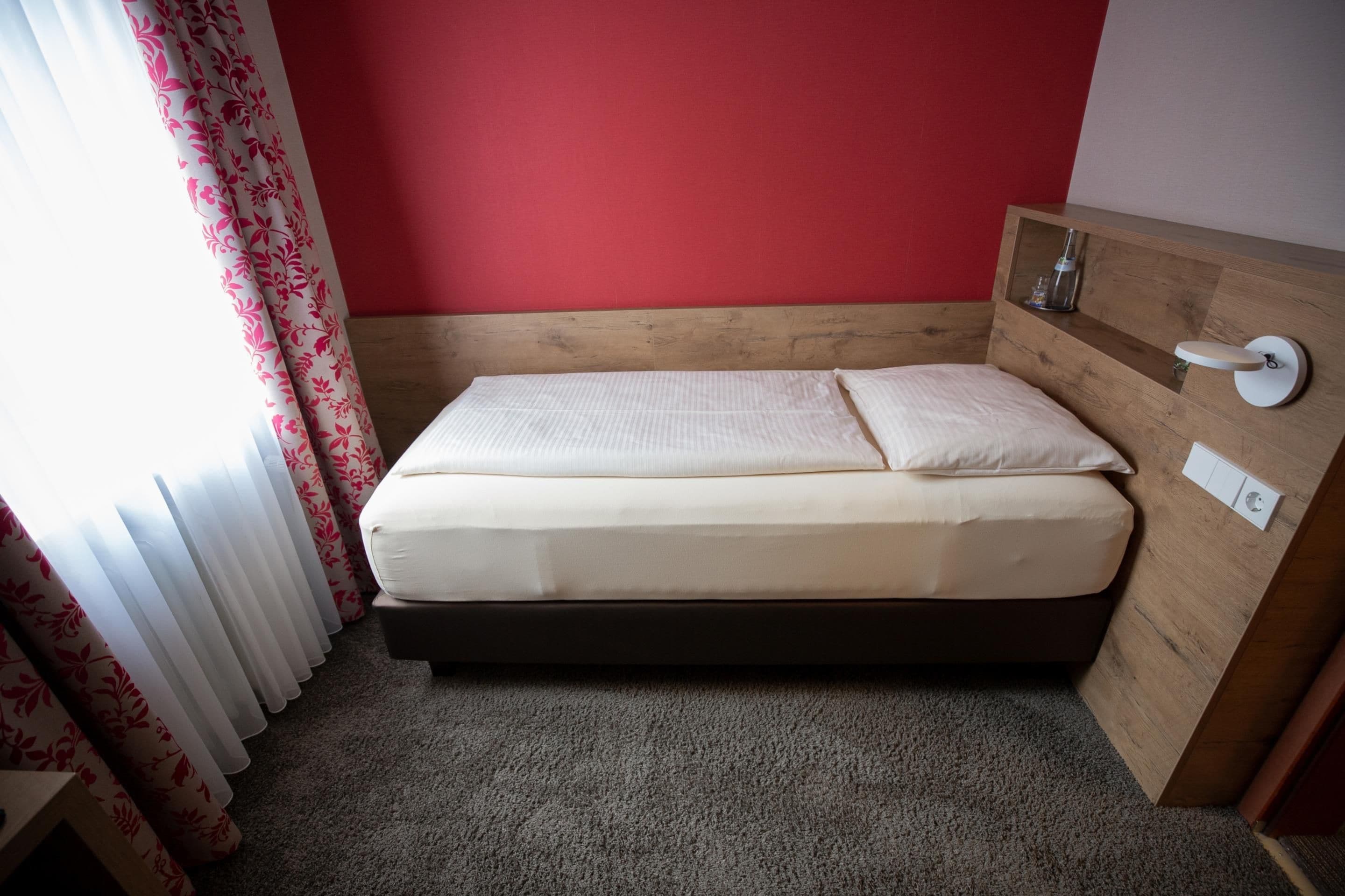 A single bed with a wooden headboard and a bedside table with a lamp.