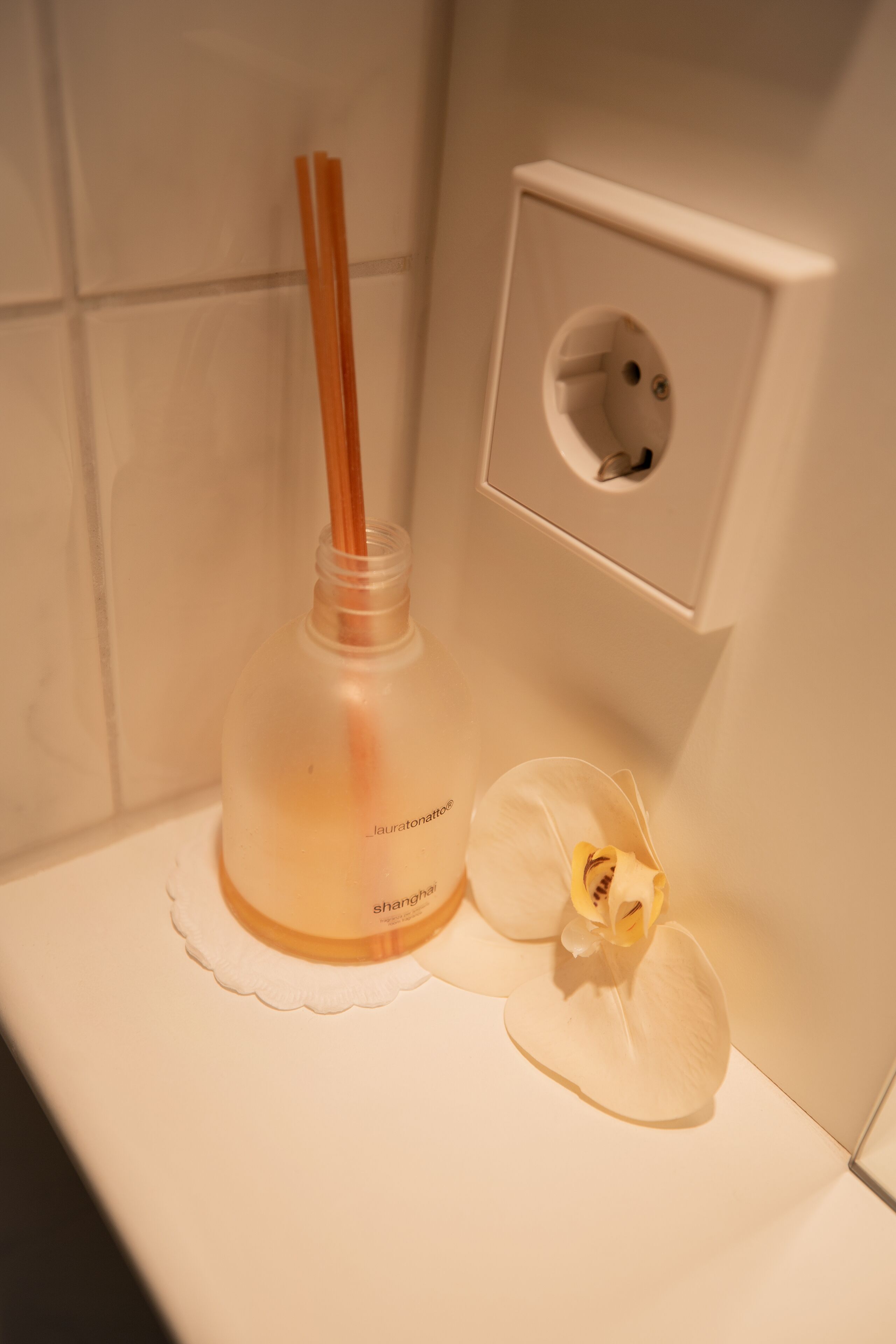 A bathroom with a bottle of shampoo and an orchid on a white surface.