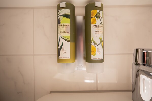 Two bottles of Naturals hand and body lotion and liquid soap on a bathroom wall. - Hotel Azenberg Stuttgart, Sure Hotel Collection by BW (Stuttgart)