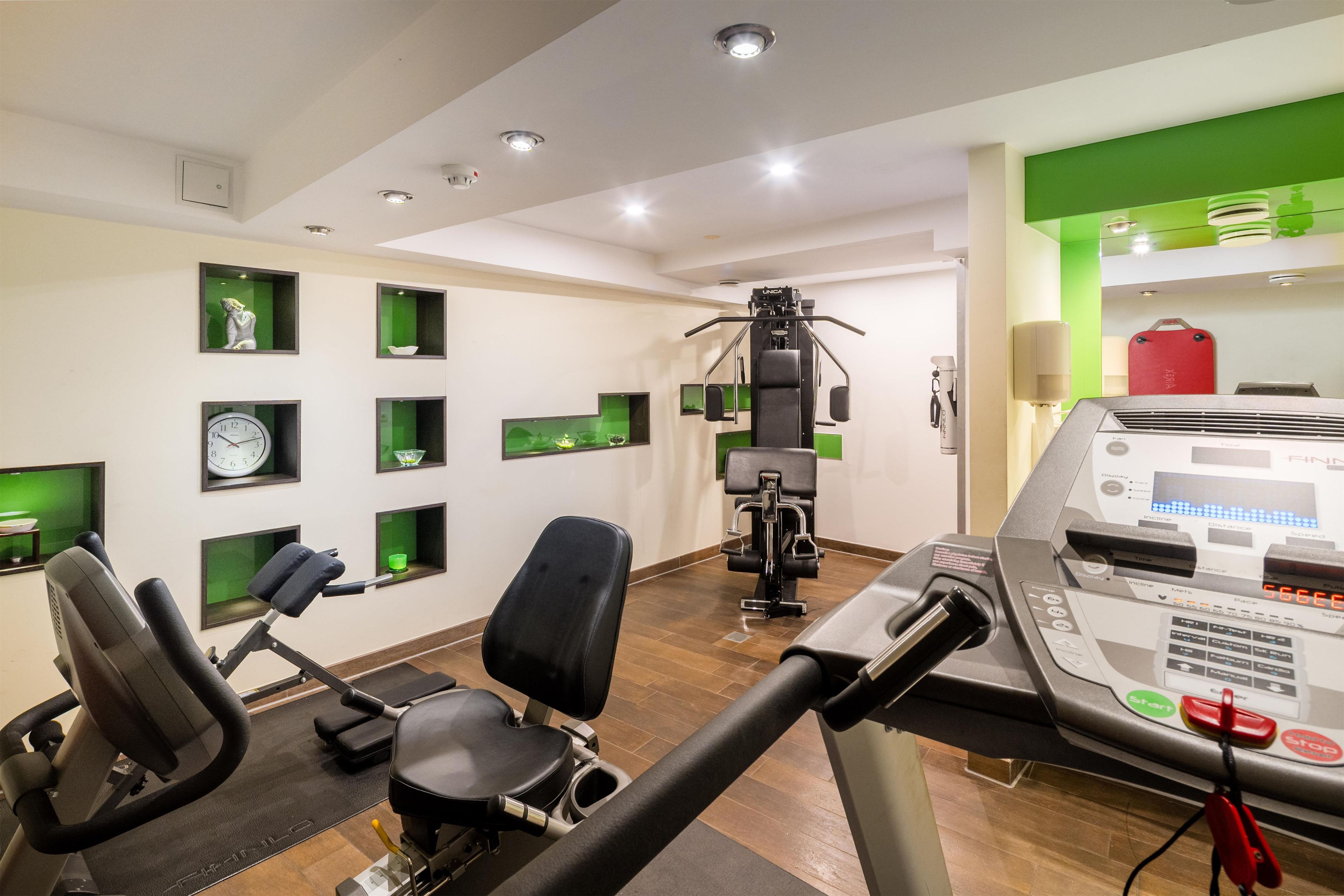 A gym with exercise equipment, a treadmill, and a wall-mounted control panel.