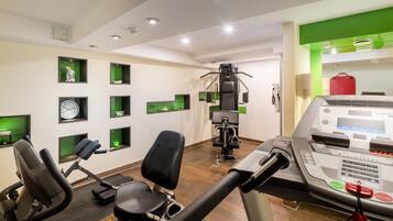 A gym with exercise equipment, a treadmill, and a wall-mounted control panel.