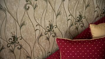 A close-up of a textured wall with a floral pattern and a red polka-dotted pillow.