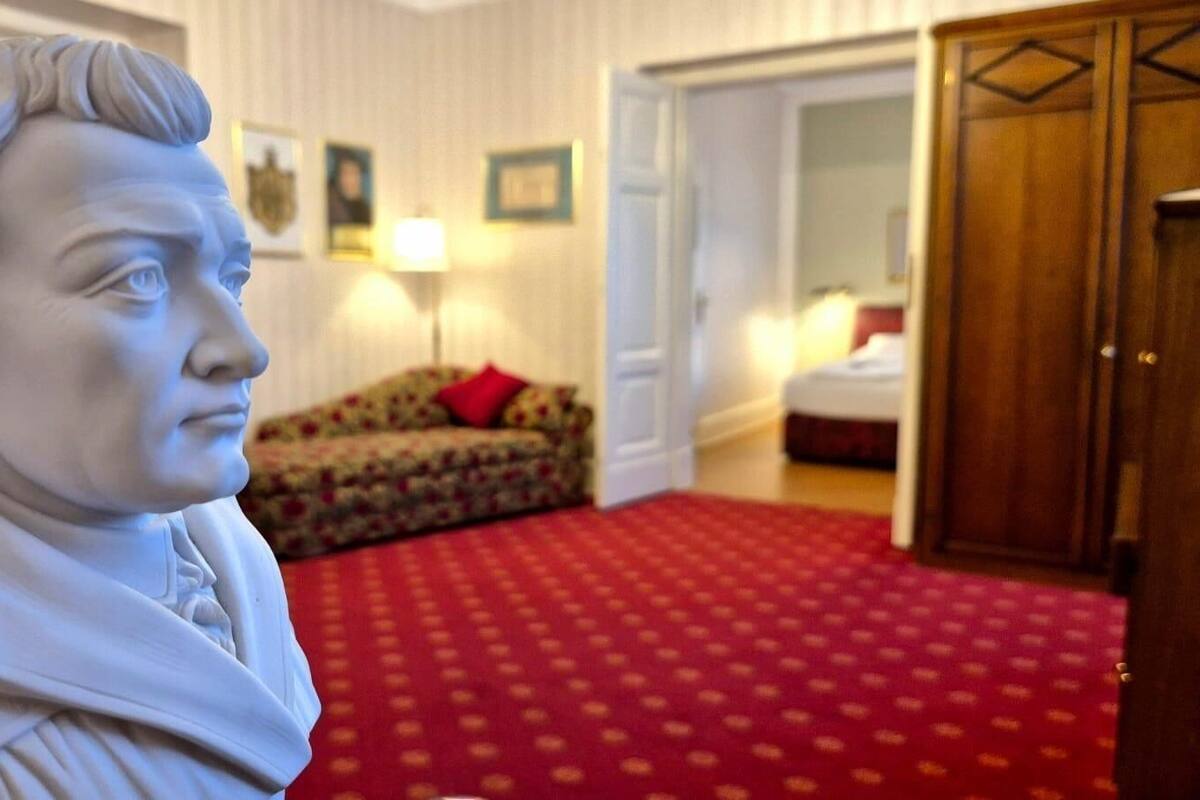 Una estatua en una habitación con alfombra estampada, un sofá y un armario de madera.
