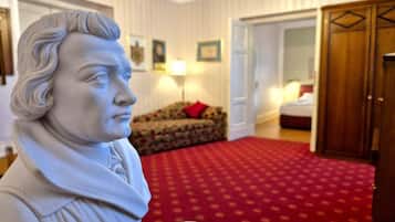 A statue in a room with a patterned carpet, a sofa, and a wooden wardrobe.