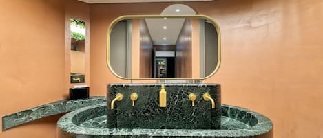 Une salle de bain avec un lavabo en marbre, des robinets dorés et un miroir au-dessus.