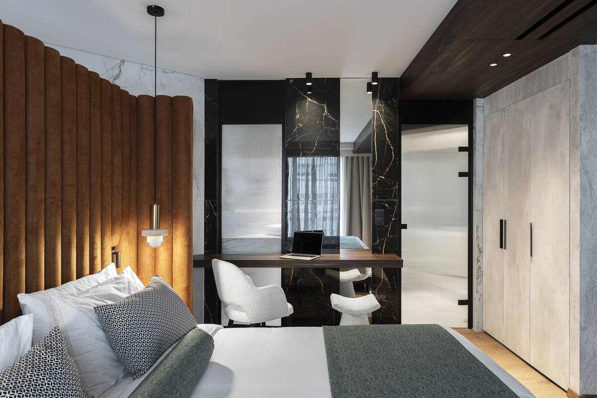 A modern bedroom with a bed, a desk, and a wardrobe.