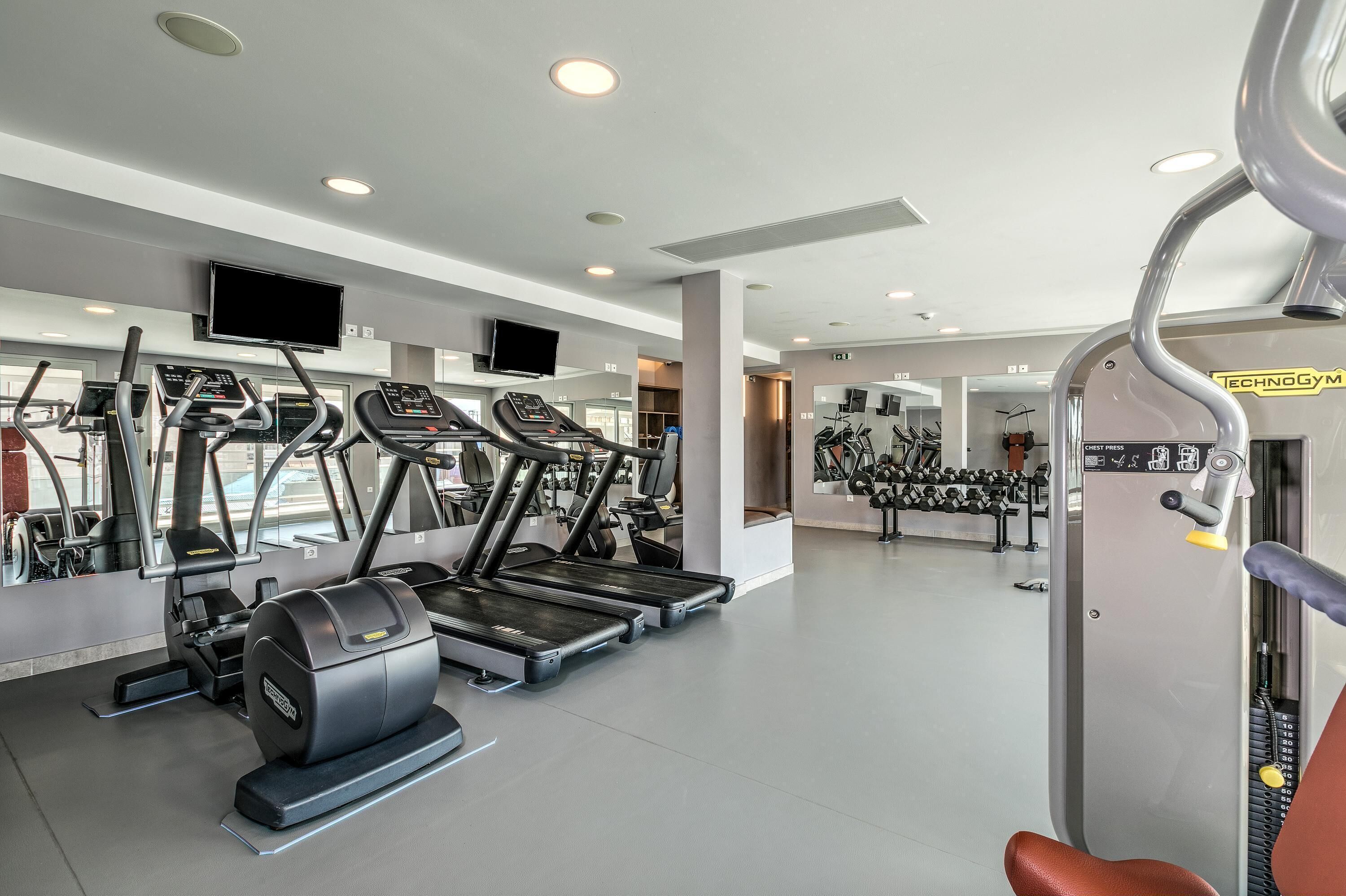 Ein modernes Fitnessstudio mit Laufbändern, Crosstrainern und Gewichten.