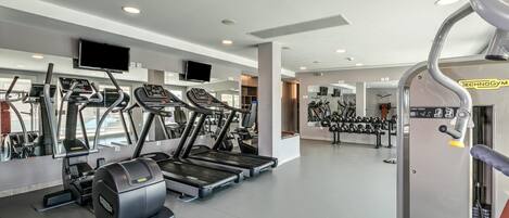 A modern gym with treadmills, elliptical machines, and weightlifting equipment.
