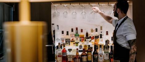 A bar area with a variety of liquor bottles and glasses on shelves.