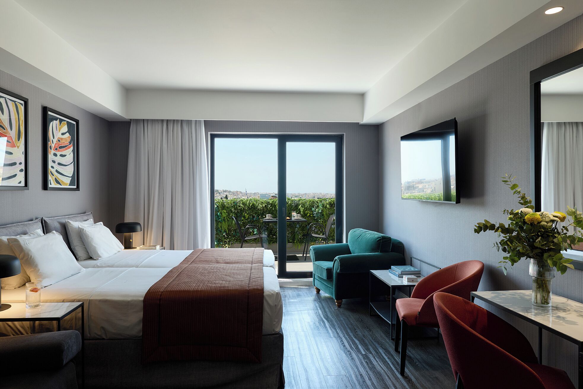 A hotel room with a bed, a desk, a chair, a TV, and a balcony with a view.