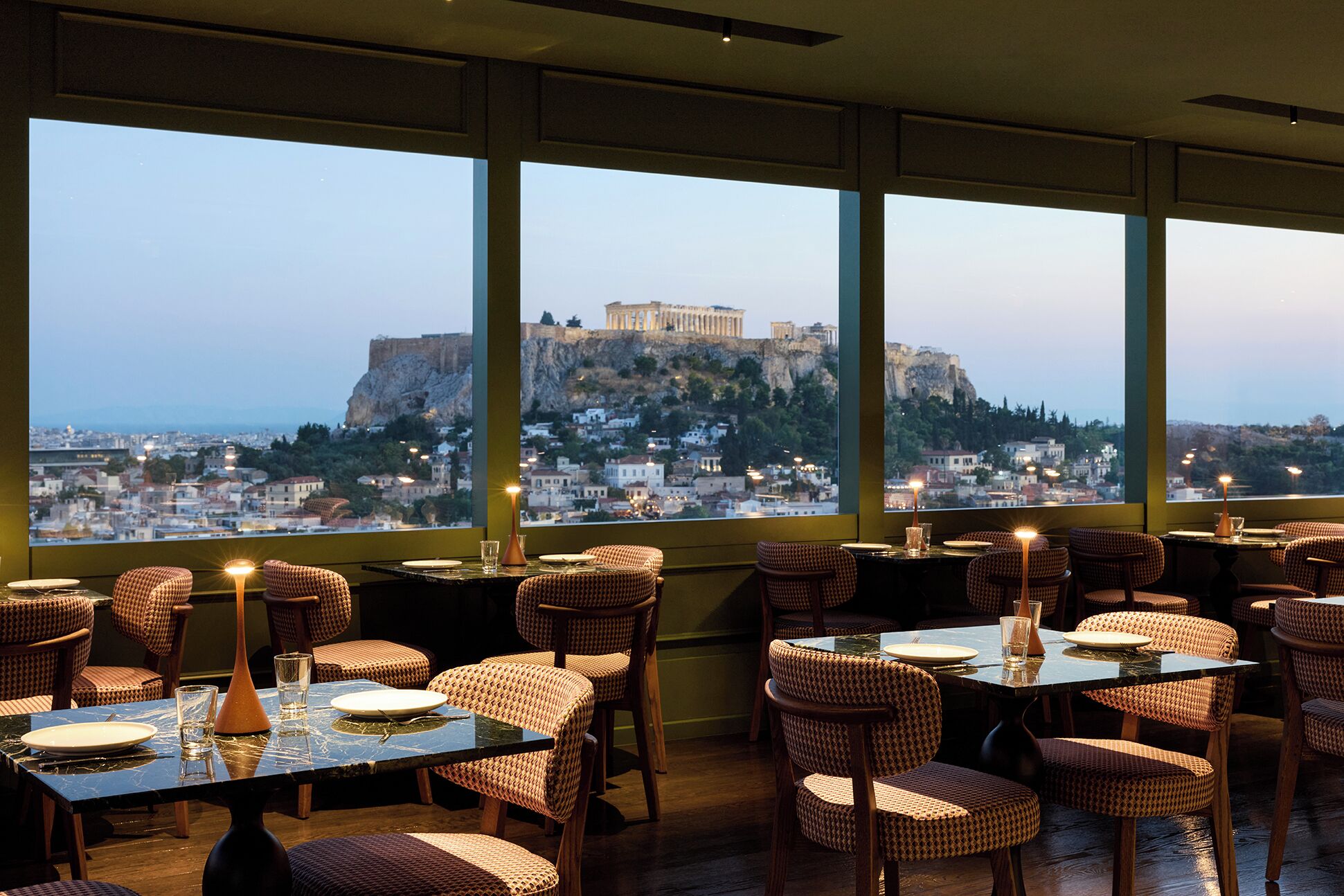 Un restaurant avec des tables et des chaises, de grandes fenêtres donnant sur un site historique.