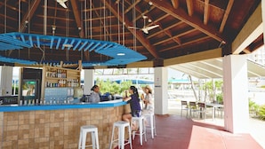 A bar area with a counter, stools, and ceiling fans.