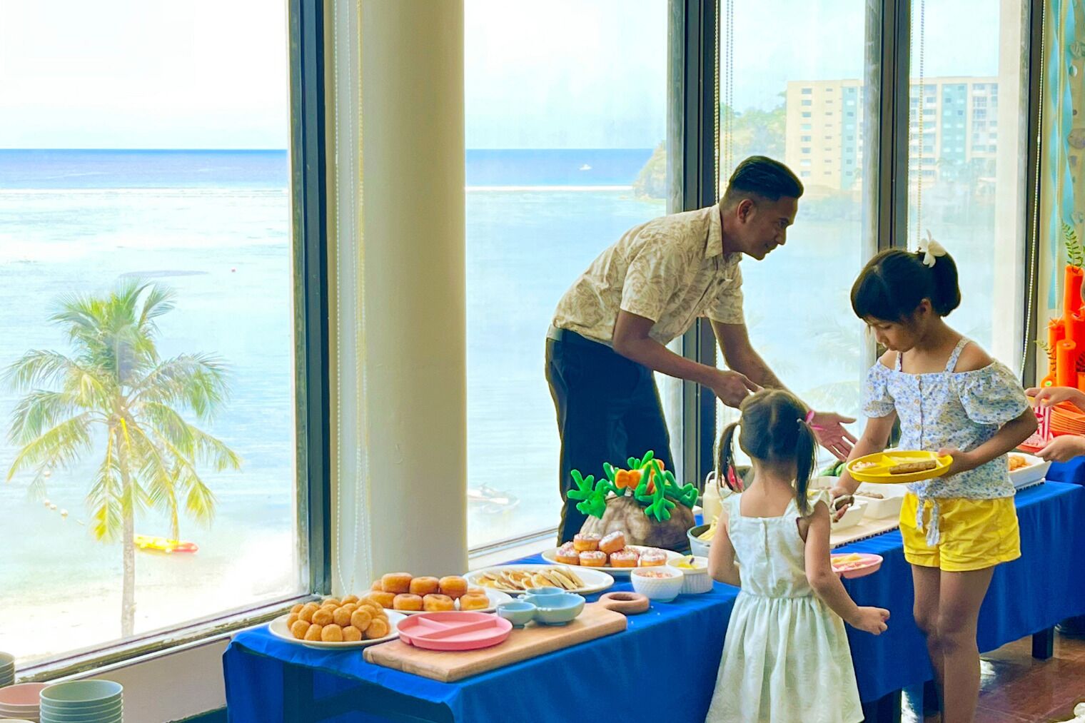 A dining area with a view of the ocean, a table with food, and a person serving food.