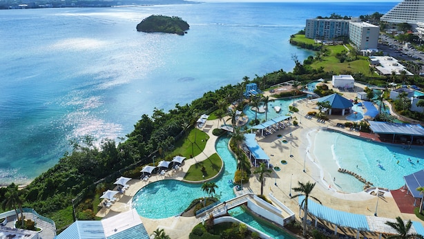 A resort with multiple swimming pools, a beach area, and a view of the ocean.