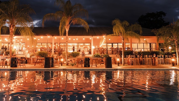 A hotel with outdoor seating, a swimming pool, and palm trees. - Copantl Hotel & Convention Center (San Pedro Sula)