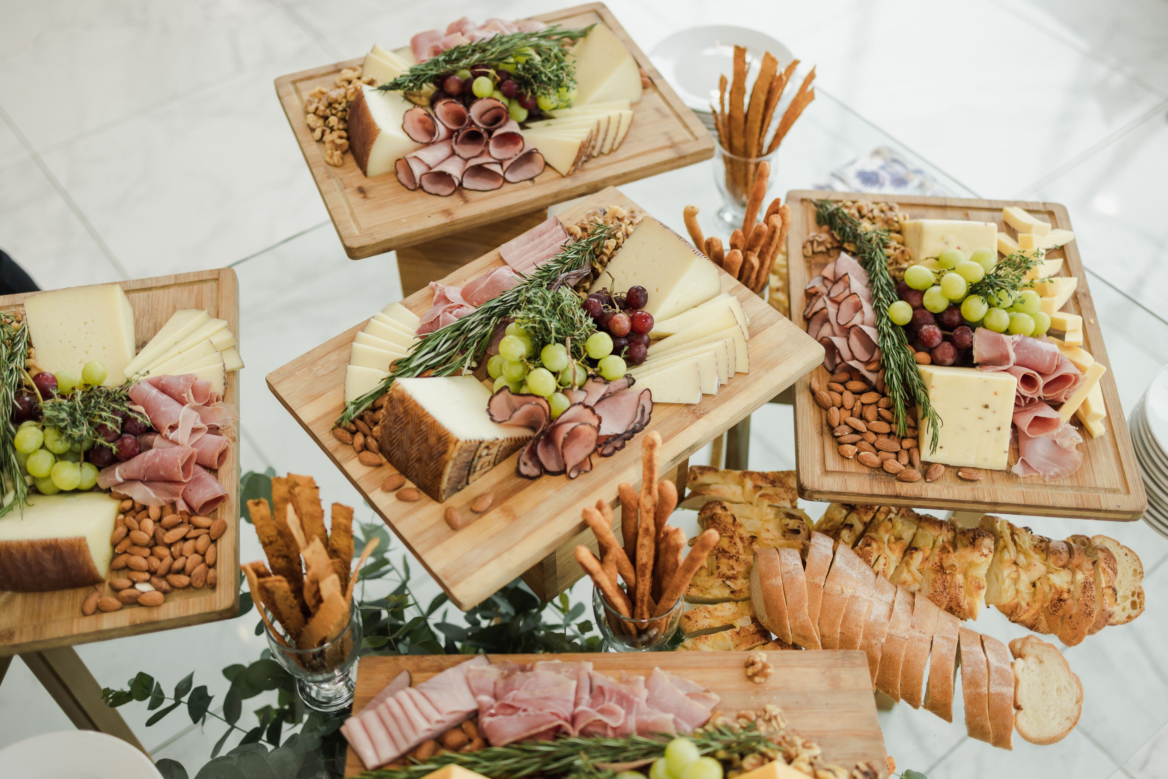 A variety of cheeses, meats, and bread on wooden boards, arranged on a table.