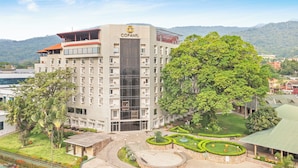 A multi-story hotel with a central courtyard, surrounded by lush greenery and a mountainous backdrop. - Copantl Hotel & Convention Center (San Pedro Sula)