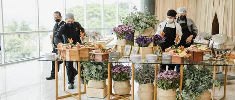 A modern dining area with a glass table surrounded by woven baskets of flowers, plates, and cutlery.